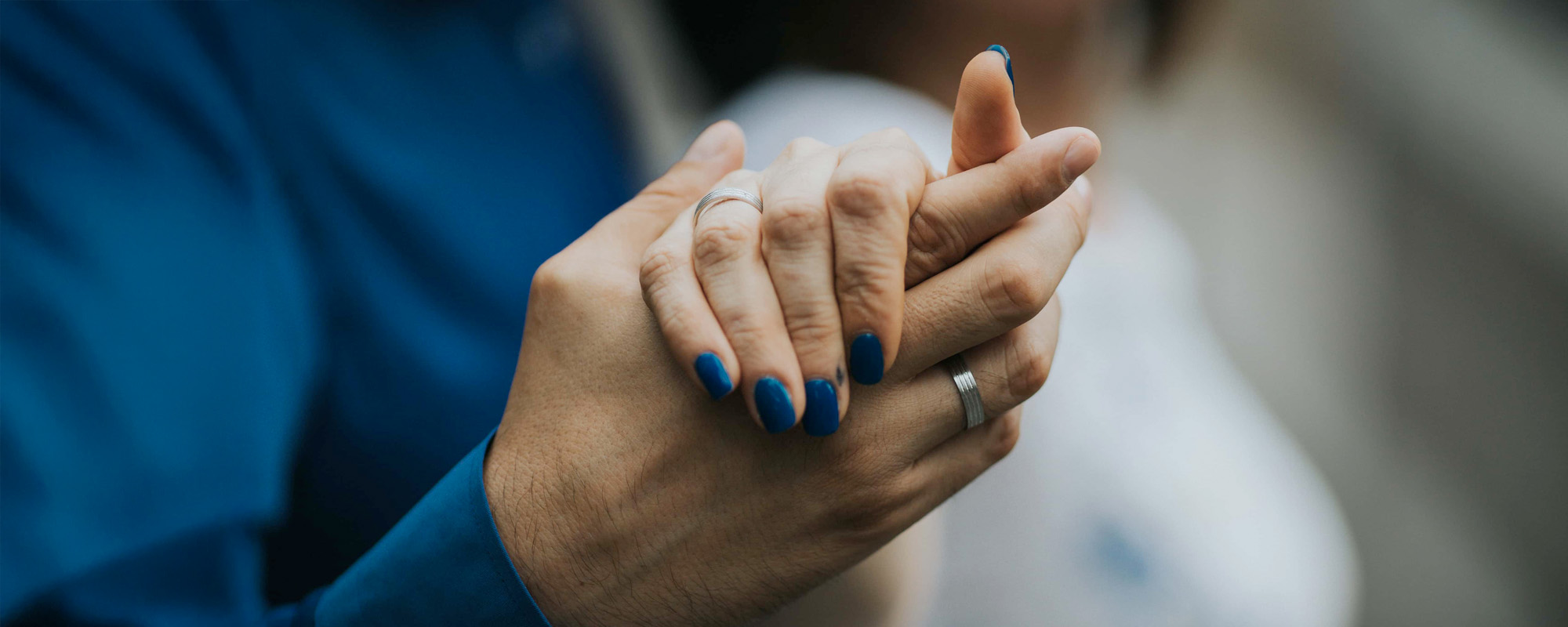 Closeup shot of a bride and groom holding hands while dancing together