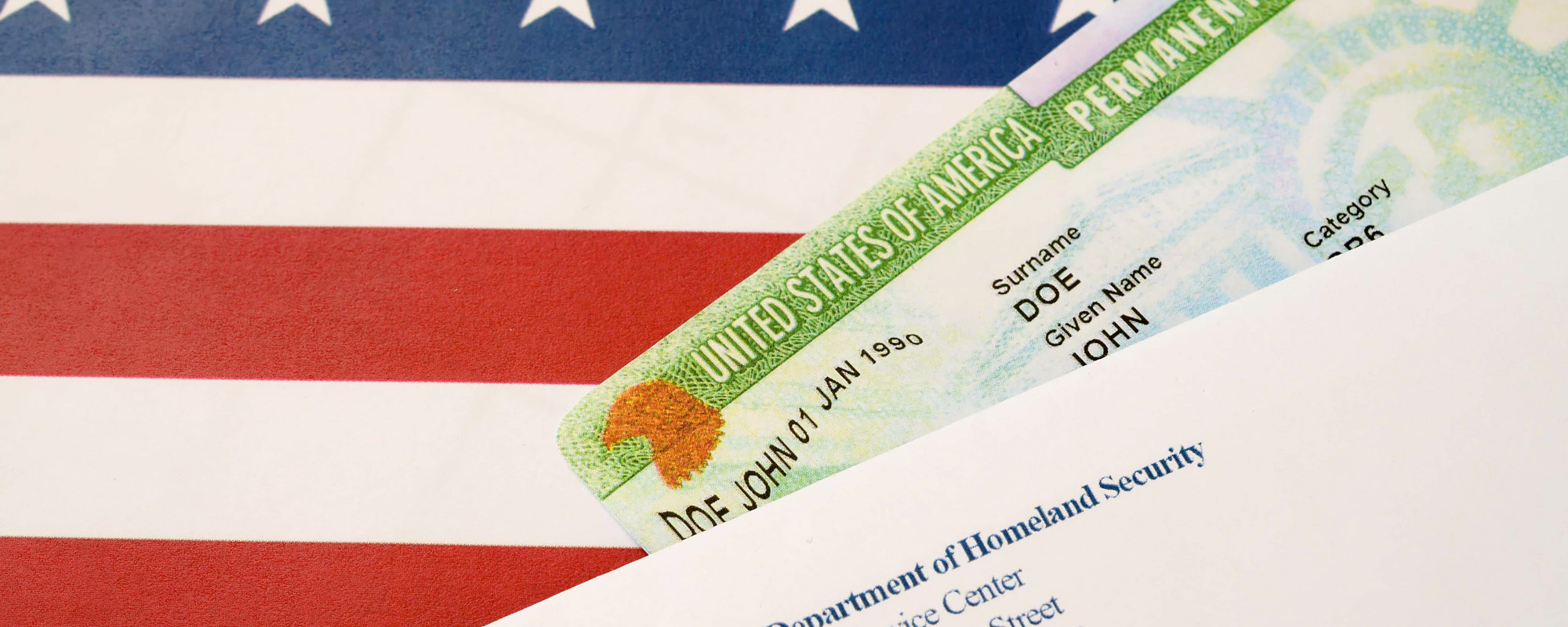 United States Permanent resident green card from dv lottery lies on United States flag with envelope from Department of Homeland Security