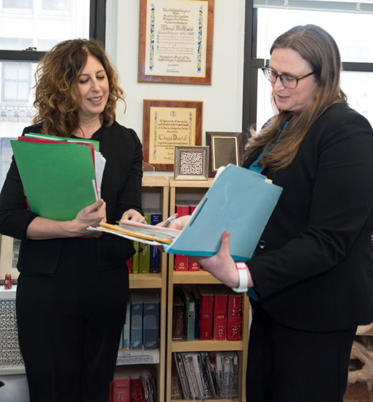 Cheryl David speaking with a staff member and holding documents
