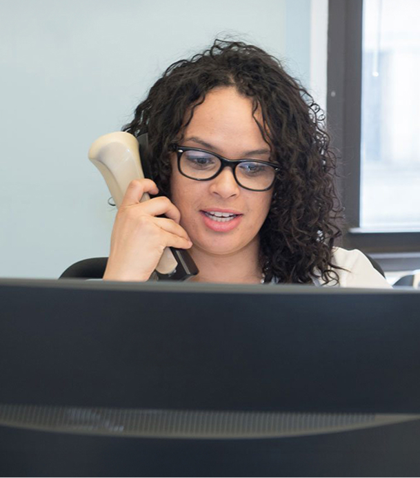 staff member on the phone and looking at a desktop computer