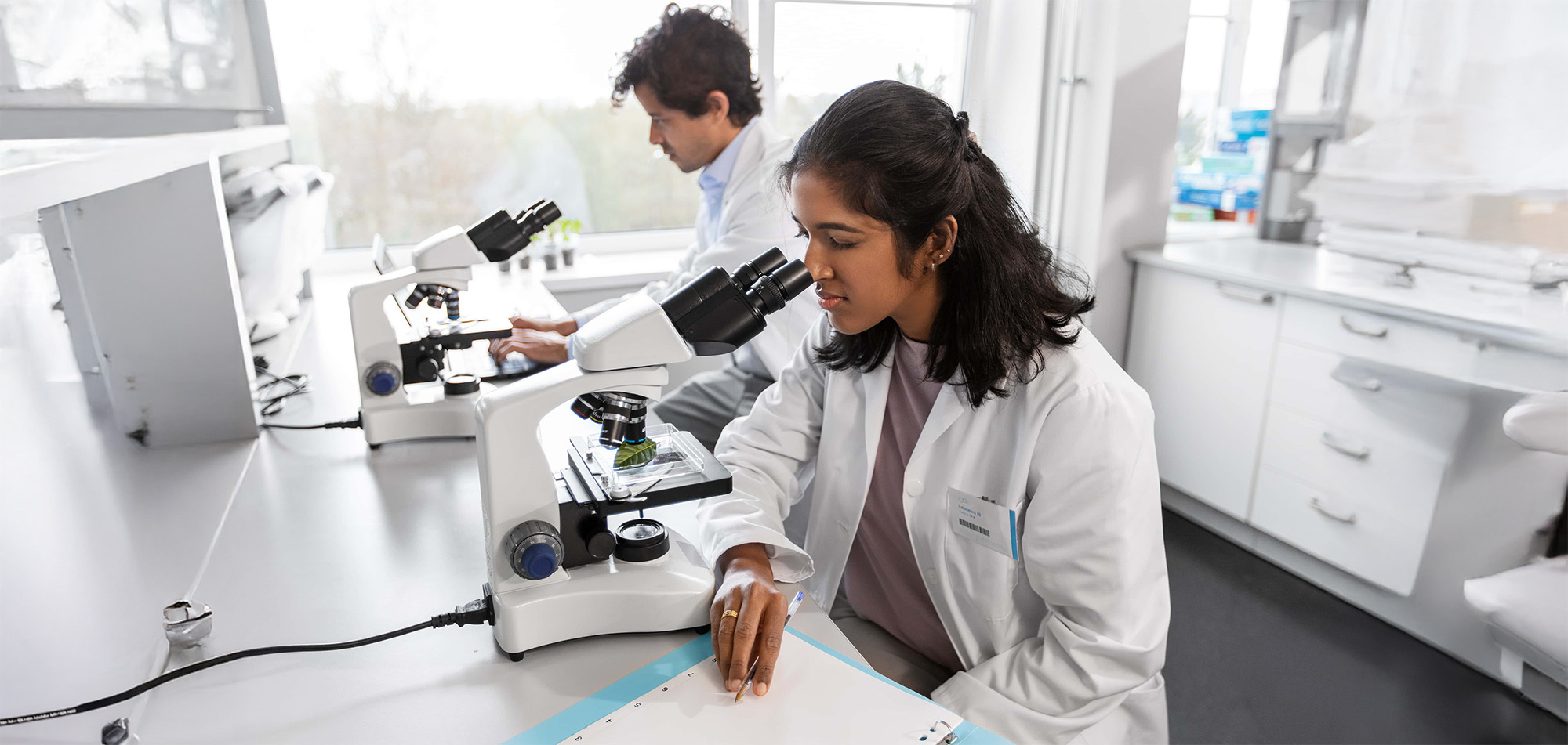 scientists with microscopes working in laboratory