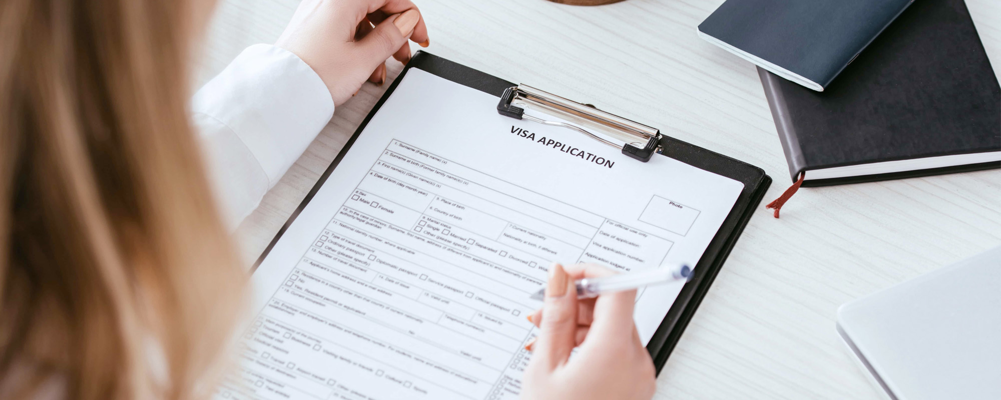 selective focus of woman holding pen near document with visa application lettering