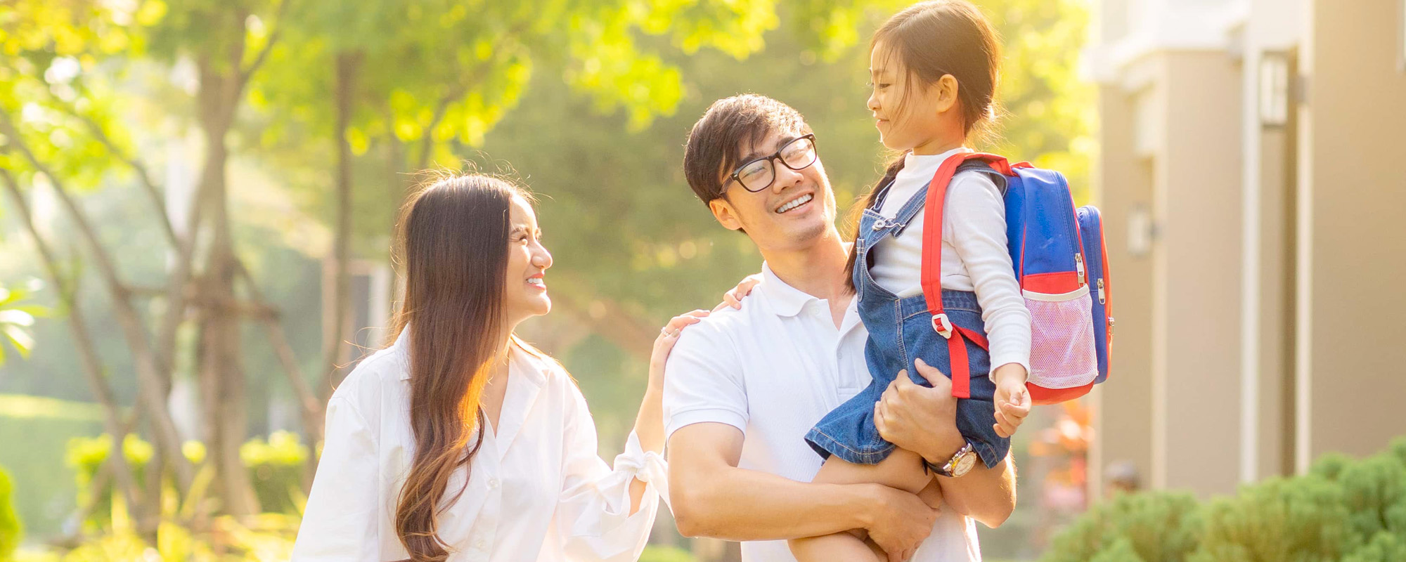 young couple holding daughter and walking down sidewalk